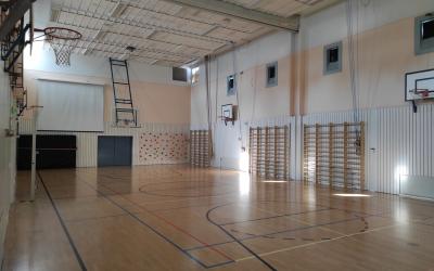 Liikuntasalissa puulattia, seinällä puolapuut ja katossa koripallotelineet