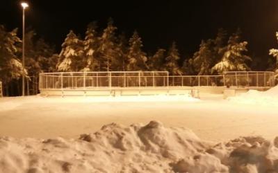 Etualalla luistelukenttä, taustalla luistelukaukalo, talvinen iltakuva