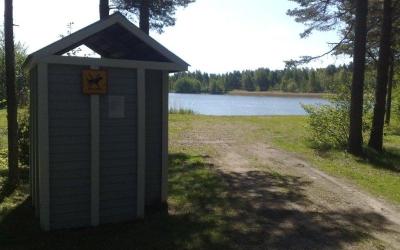 Pukukoppi sekä polku uimarannalle, taustalla näkyy järvi