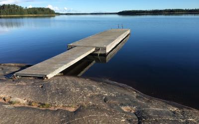 Kalliolta alkava laituri siniselle järvelle, takana siintää puita