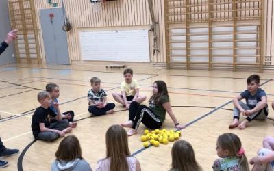 Opettaja ja oppilaat piirissä liikuntasalin lattialla.