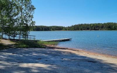 kallion takana siintää laituri ja järvi sininen kesätaivas