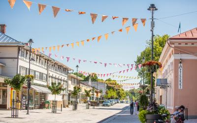 Alinenkatu kesällä 2023, värikkäät viirit auringossa kylpevän kadun yllä. 