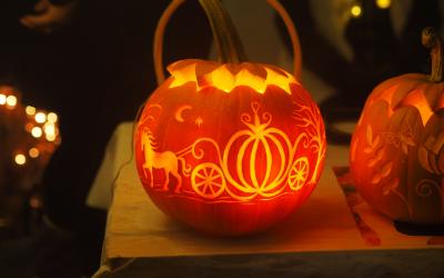 Kaiverrettu ja valaistu oranssi Halloween -kurpitsa pöydällä.