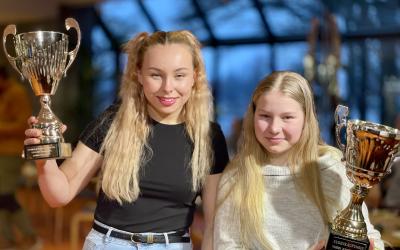 kaksi tyttöä esittelee voittopokaaleitaan