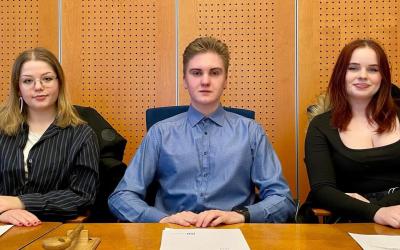 nuorisovaltuuston puheenjohtajiston kolme nuorta istuu pöydän ääressä