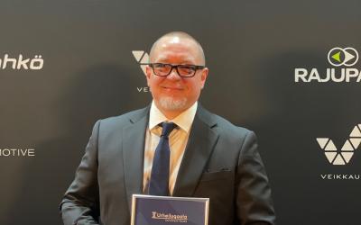 mies poseeraa palkinnon kanssa urheilugaalassa