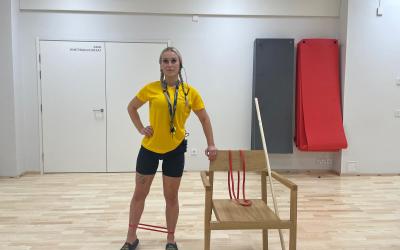 nainen ohjaa tasapainojumppa seisten, vierellä tuoli