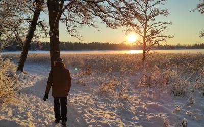 talvimaisemassa henkilö kävelee auringonlaskussa