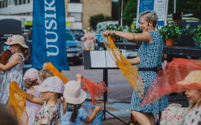 Lapset tanssivat torilla värikkäiden huivien kanssa.
