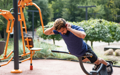 Mies kuntoilee ulkokuntosalilla, tekee selkälihaksia. Taustalla näkyy ulkokuntosalilaitteita.