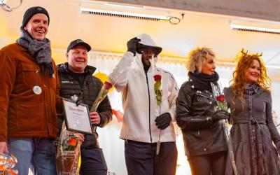 Ihmisiä rivissä lavalla ruusut kädessään.