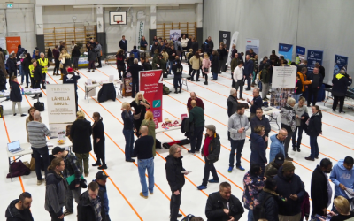 Iso määrä ihmisiä yläviistosta kuvattuna sisäliikuntahallissa juttelemassa.