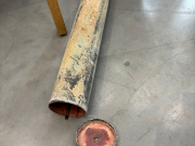 Vanha kuparinen aikakapseli lattialla, kansi avattuna.