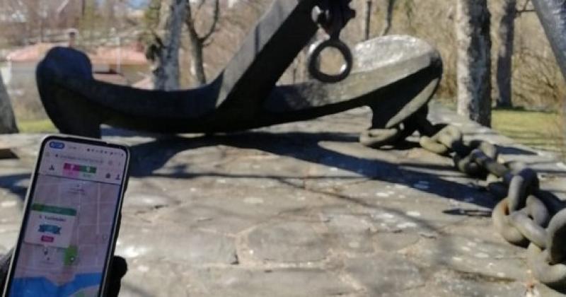 Puhelimen näyttö, jonka takana näkyy vanha ankkuri.