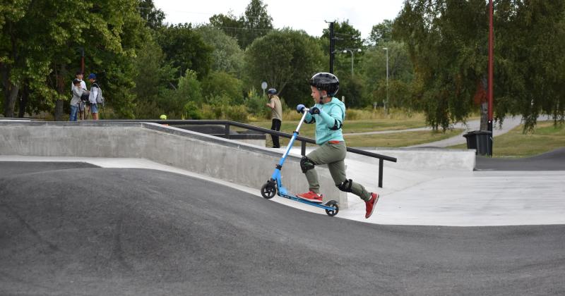 Pumptrack-rata, pieni poika skuutin kanssa.