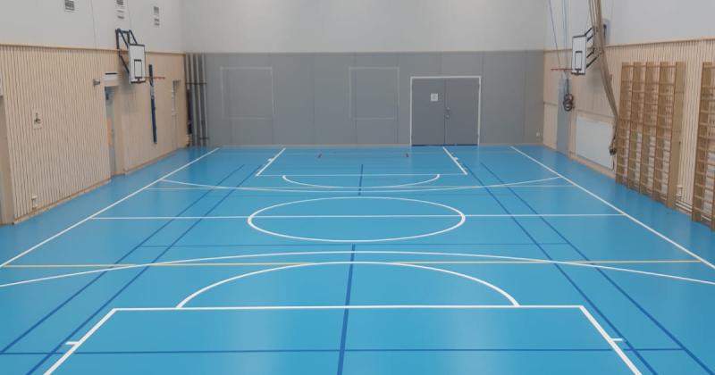 Sisäliikuntasalissa sininen lattia ja reunalla puolapuut