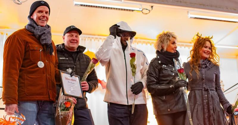 Ihmisiä rivissä lavalla ruusut kädessään.