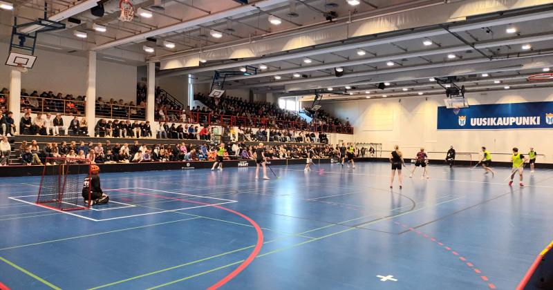 liikuntasalissa pelataan salibandyä taustalla katsomo