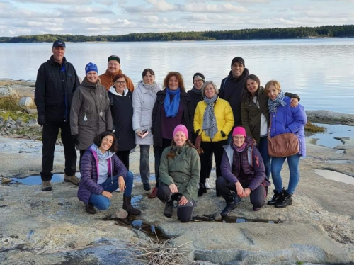 Opettajia ryhmäkuvassa kallioisella rannalla.