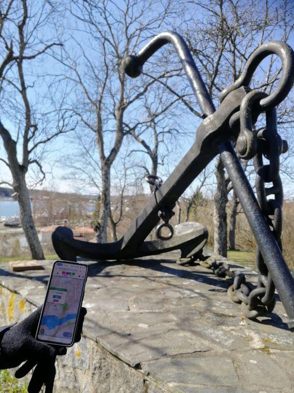 Taustalla vanha ankkuri ja edustalla puhelin, jonka näytöllä on kartta.