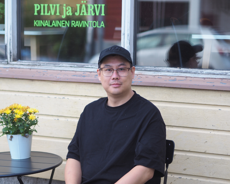 Kun Zhao istuu ravintolansa edessä ja katsoo kohti.