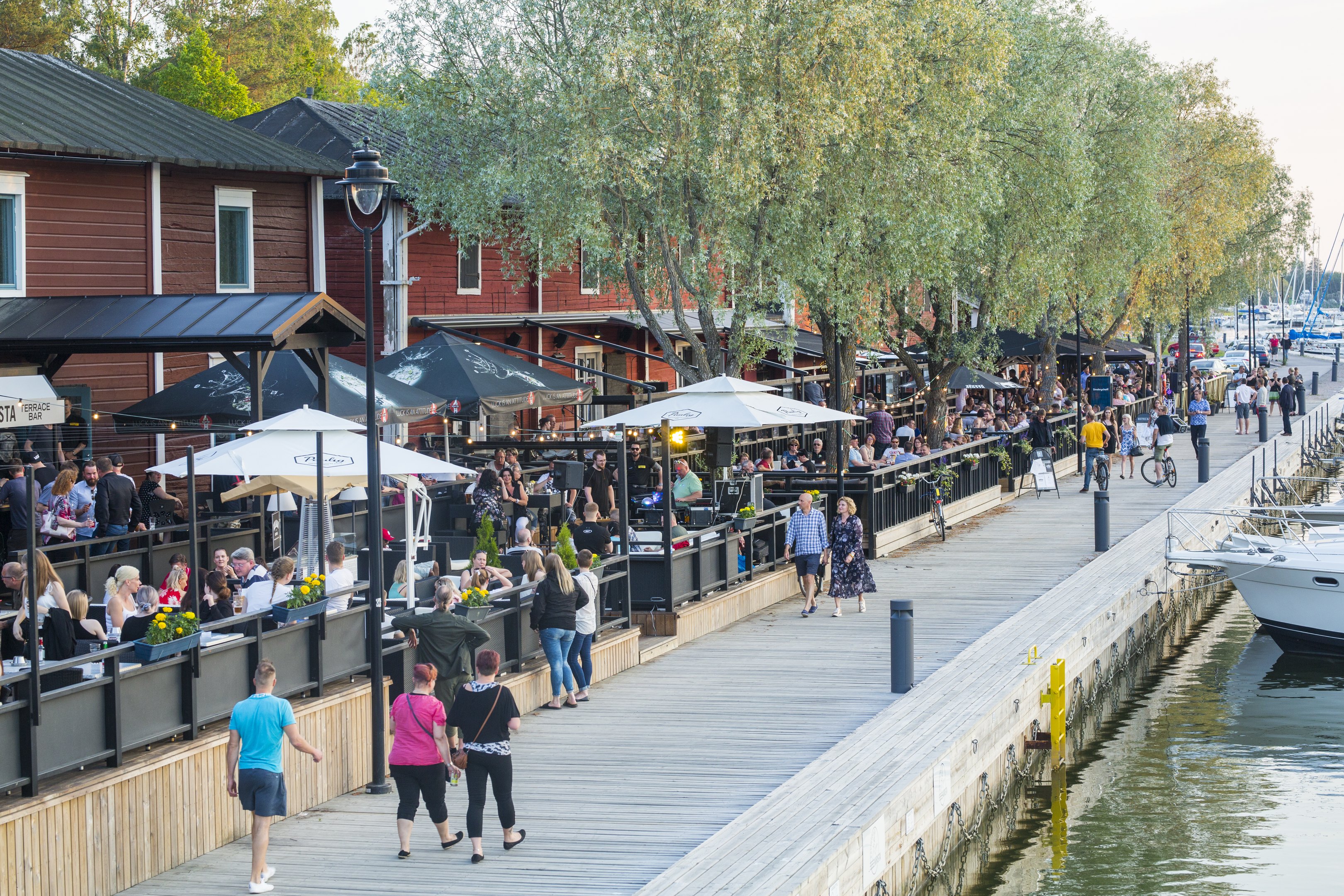 Uudenkaupungin rantamakasiinit ja pljon ihmisiä terasseilla sekä kävelemässä terassien ohi